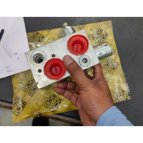 JCB backhoe valve replacement part held in hand with red knobs and metallic finish