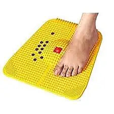 Acupressure magnet mat with yellow pyramid spikes, foot resting on surface