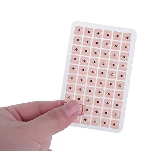 Ear seed acupressure kit sheet with small beige seed patches on grid