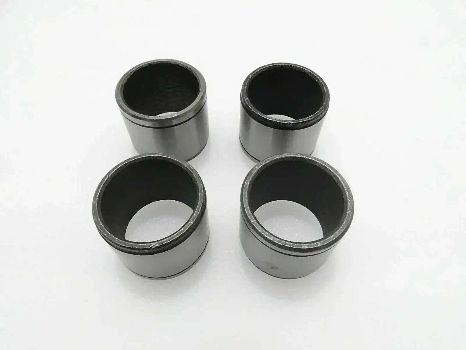 Set of 4 metal cylindrical bushes with dark inner bores