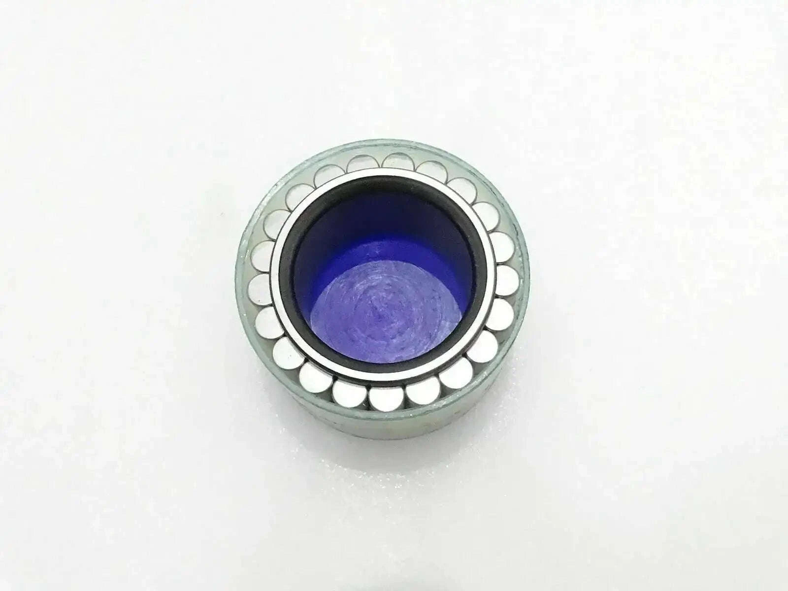 Metal roller bearing with green outer ring and purple inner race