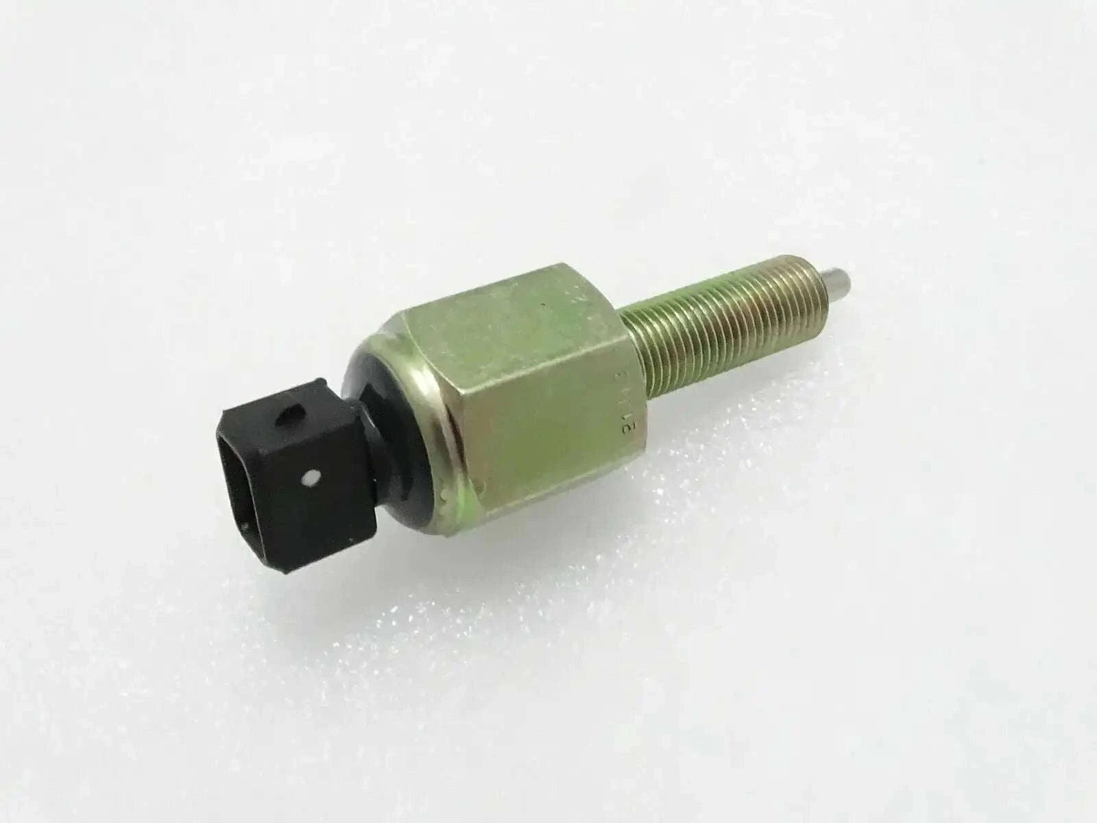 Foot brake switch with green hex body, threaded stud, and black electrical plug