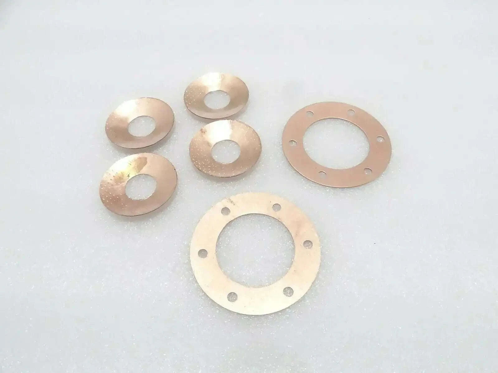 Metal thrust washers set with circular seal plates and center openings, copper-toned
