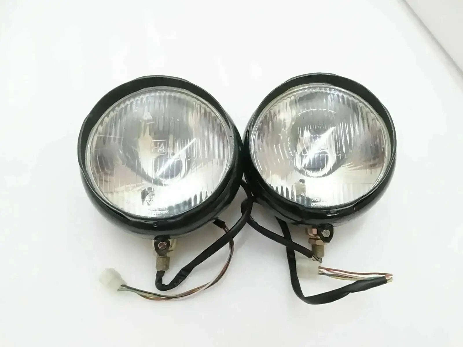Pair of round bumper headlights with clear lens, black housing, and wiring harness