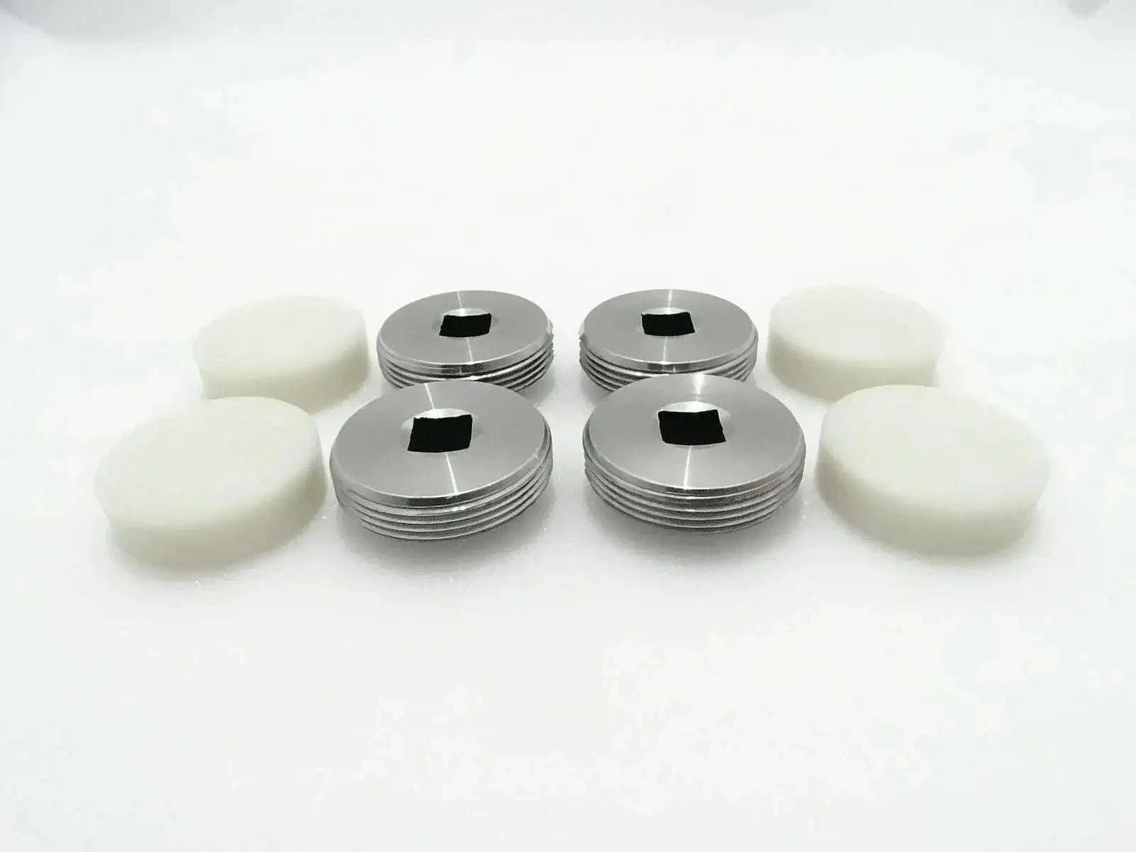 Set of 4 wear pads with white bases and silver metal caps.