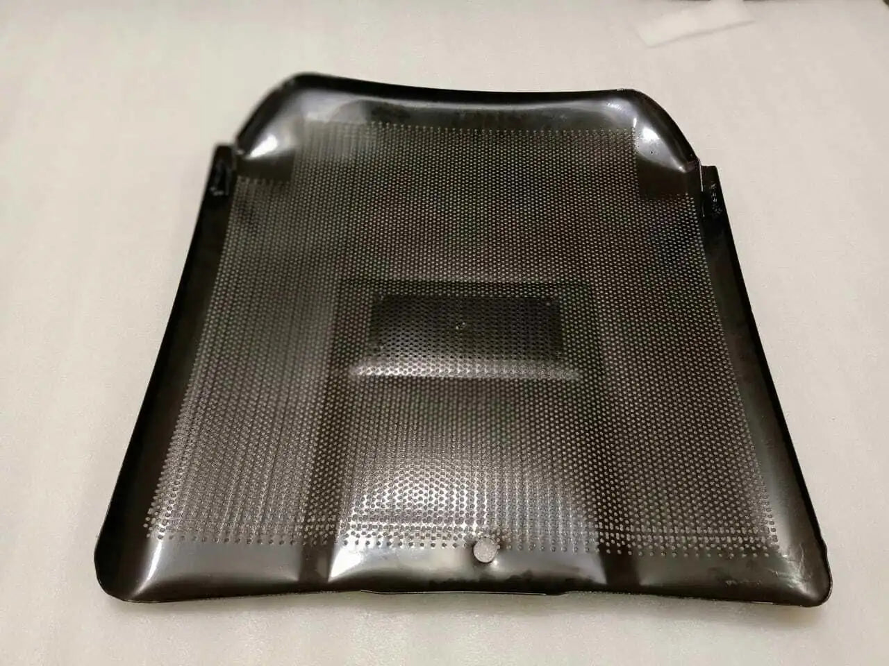 Front grill panel with perforated mesh and central rectangular opening, dark gray