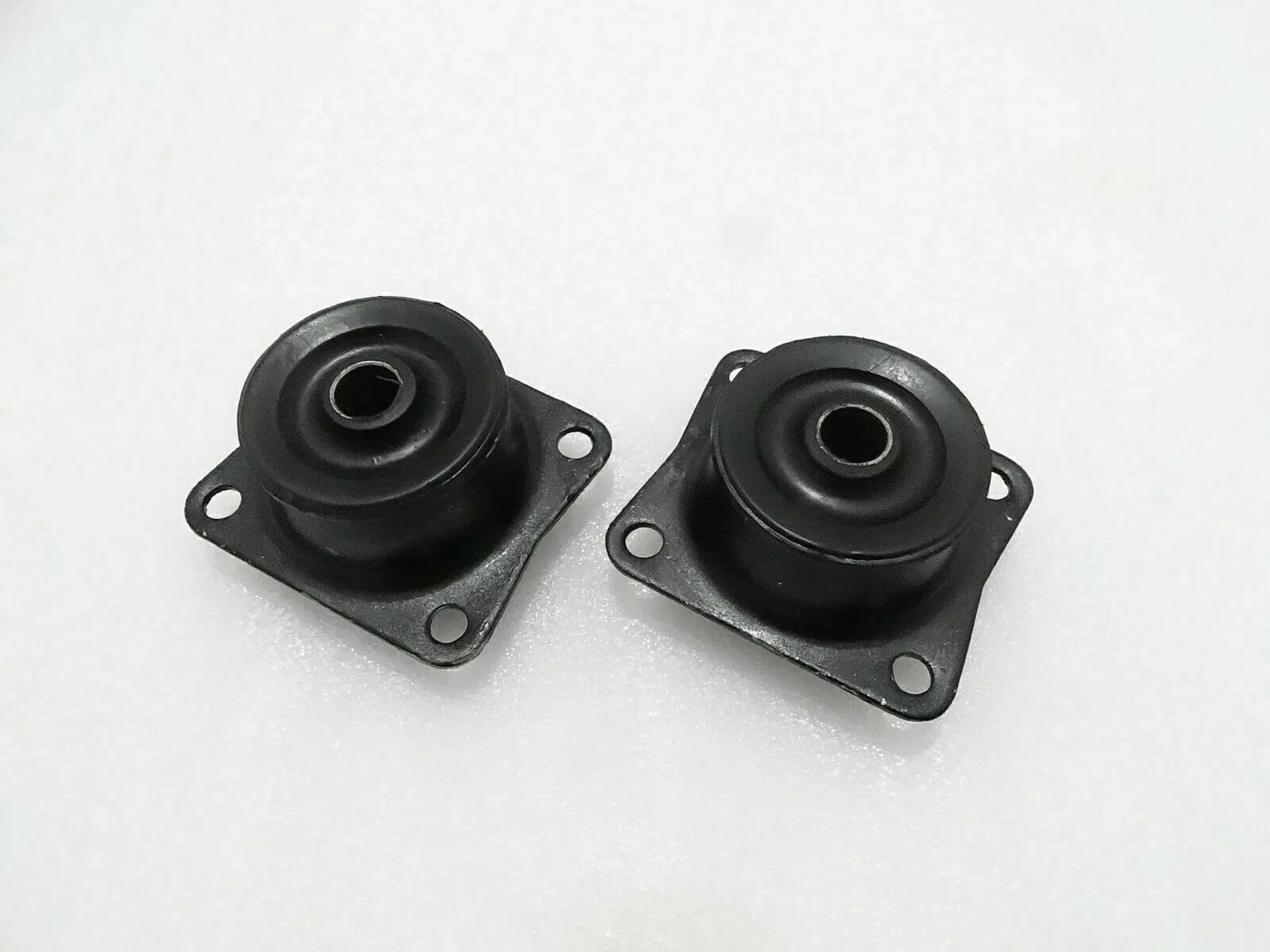 Pair of black rubber mounts with metal plates, mounting holes, and central eyelets