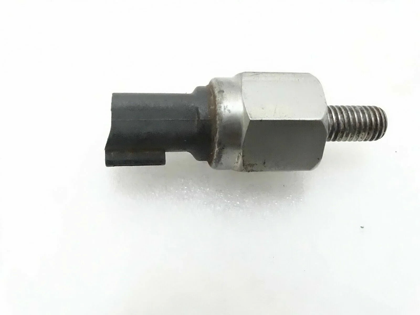 Oil pressure switch with hex metal body, black connector, and threaded stud