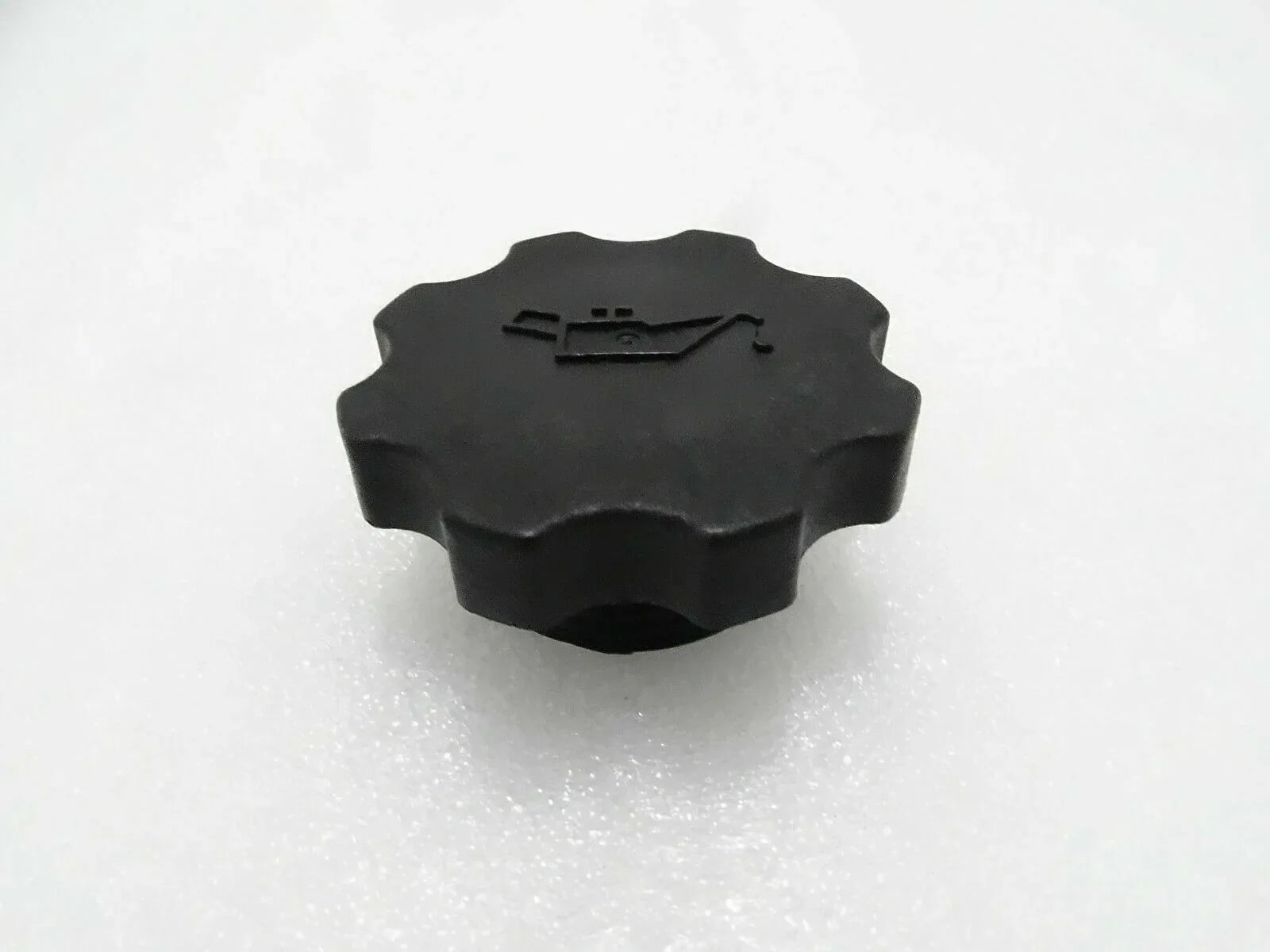 Black engine oil filler cap with ridged circular top and embossed pull tab