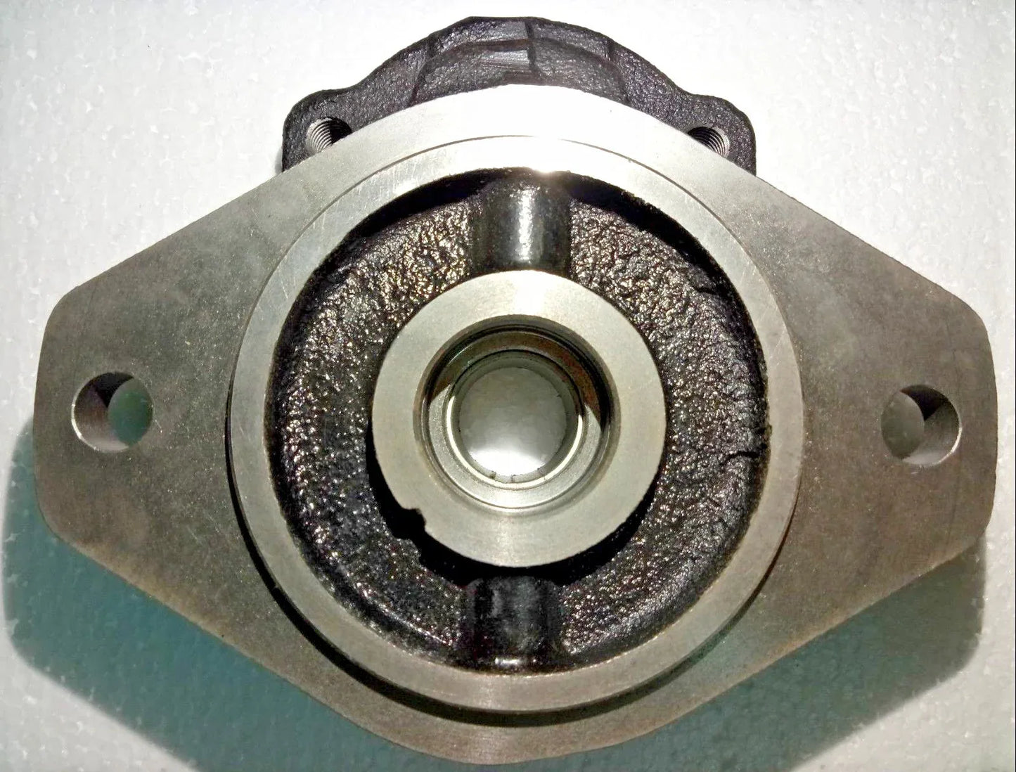 Hydraulic pump mounting flange with central bearing seal, metal body with side bolt holes