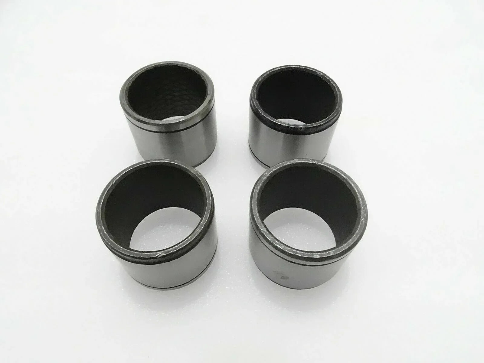 Set of 4 metal cylindrical bushes with dark inner bores