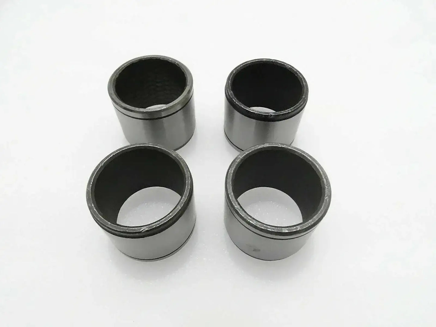 Set of 4 metal cylindrical bushes with dark inner bores