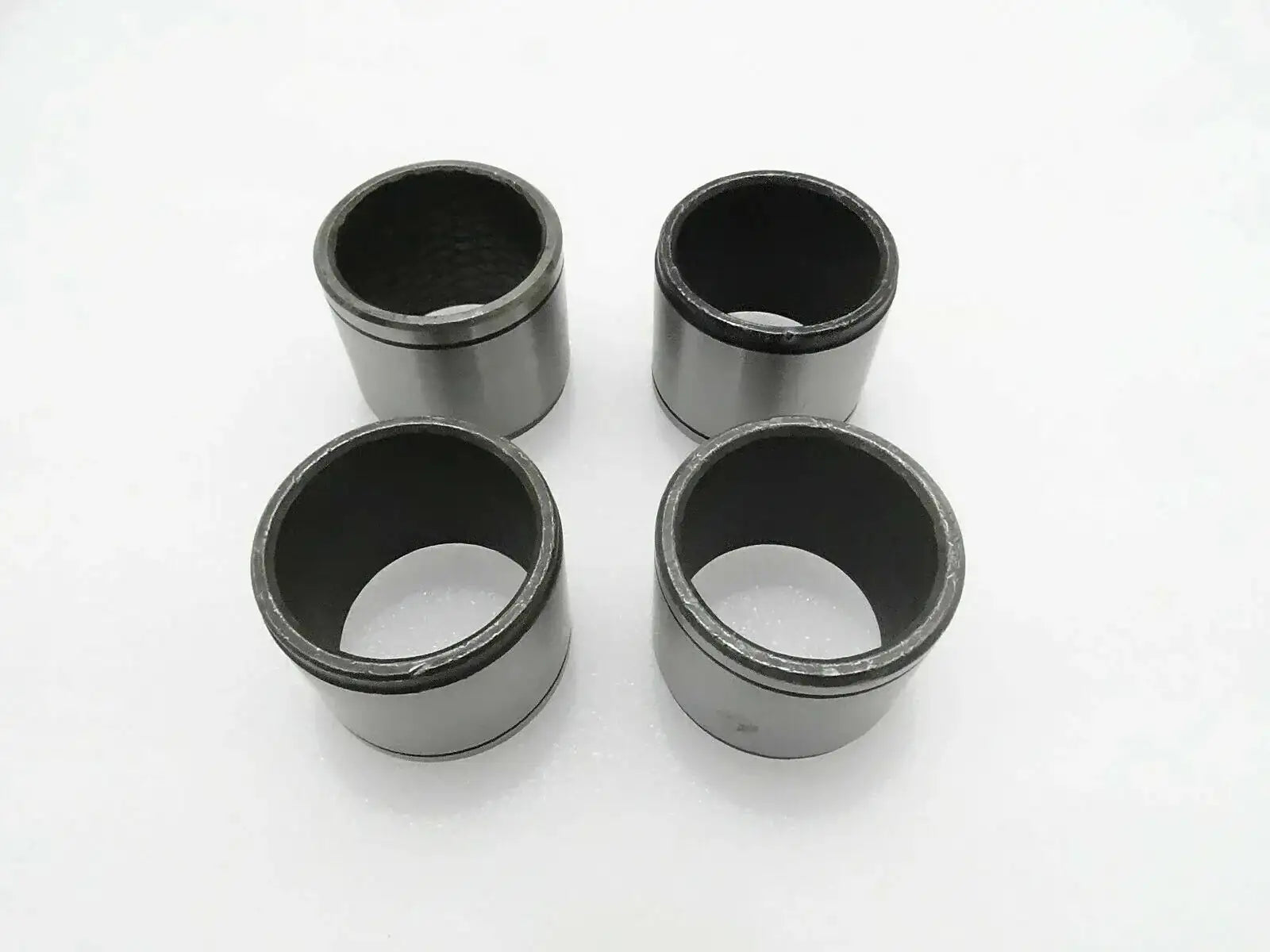 Set of 4 metal cylindrical bushes with dark inner bores