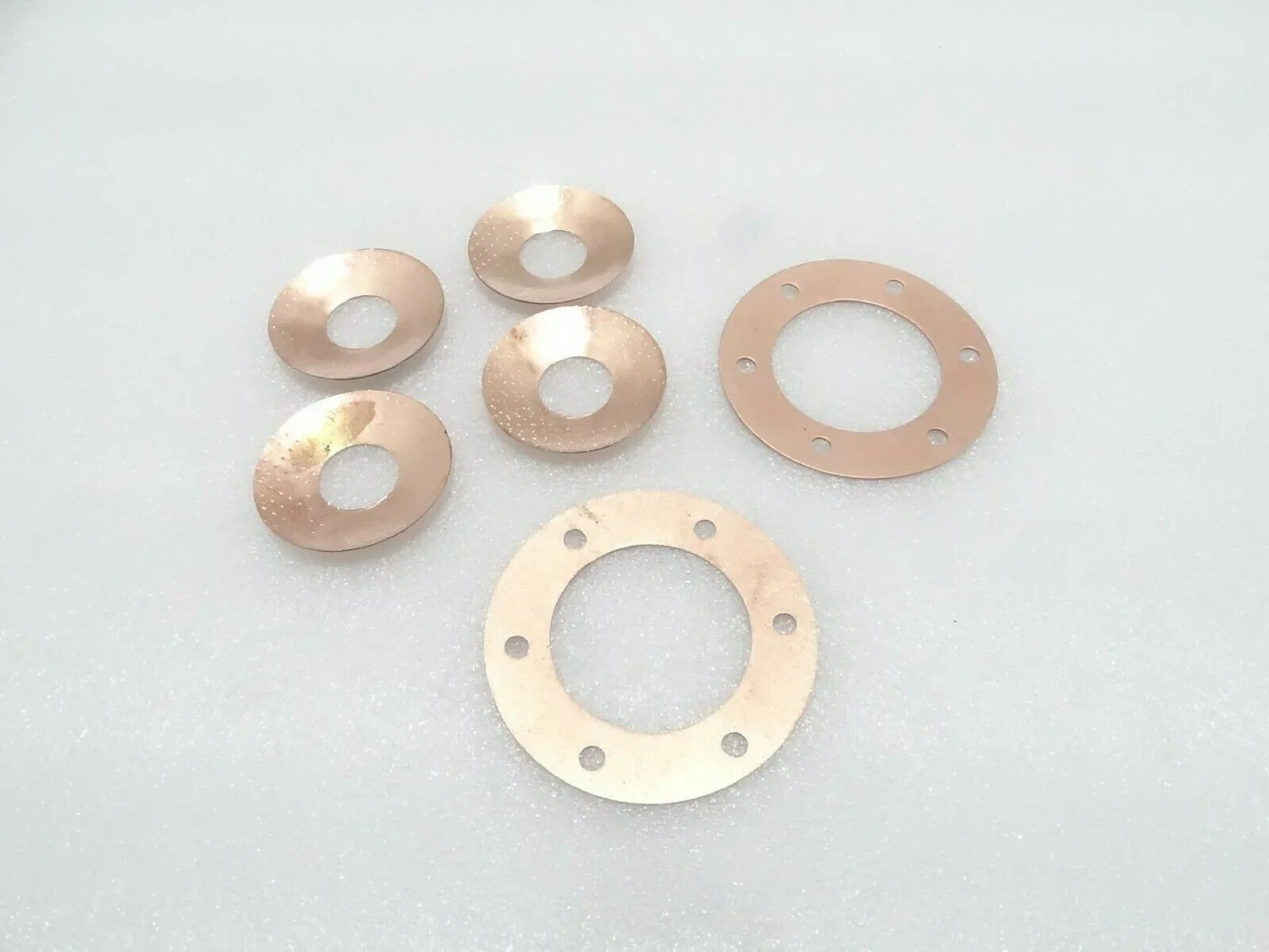 Metal thrust washers set with circular seal plates and center openings, copper-toned