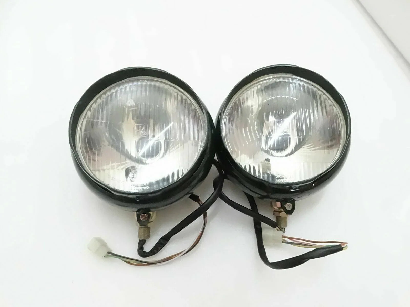 Pair of round bumper headlights with clear lens, black housing, and wiring harness