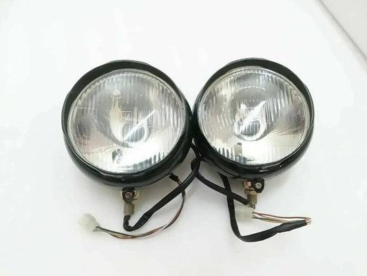 Pair of round bumper headlights with clear lens, black housing, and wiring harness