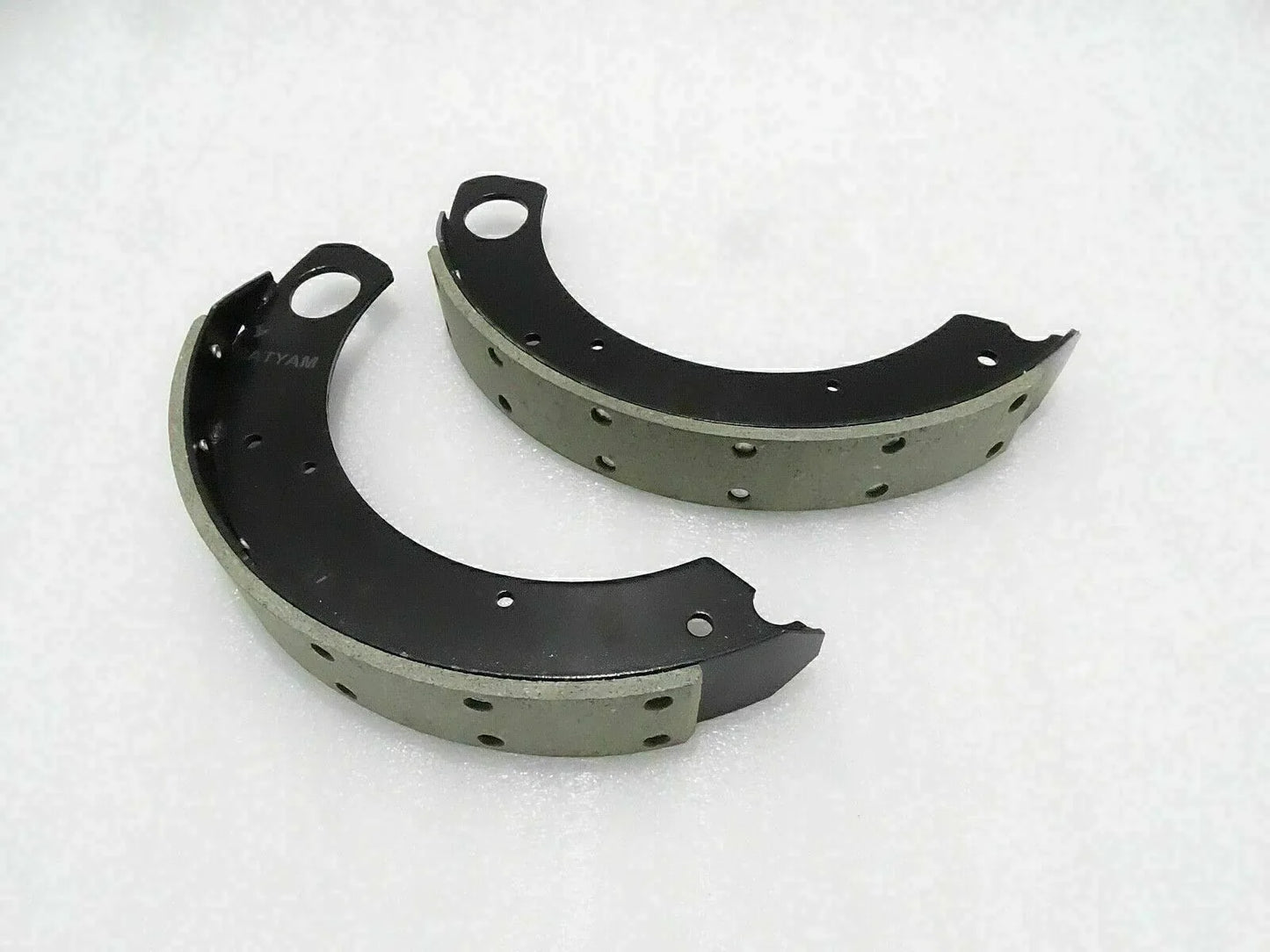 Curved tractor brake shoe lining set with black metal backing and rivet holes