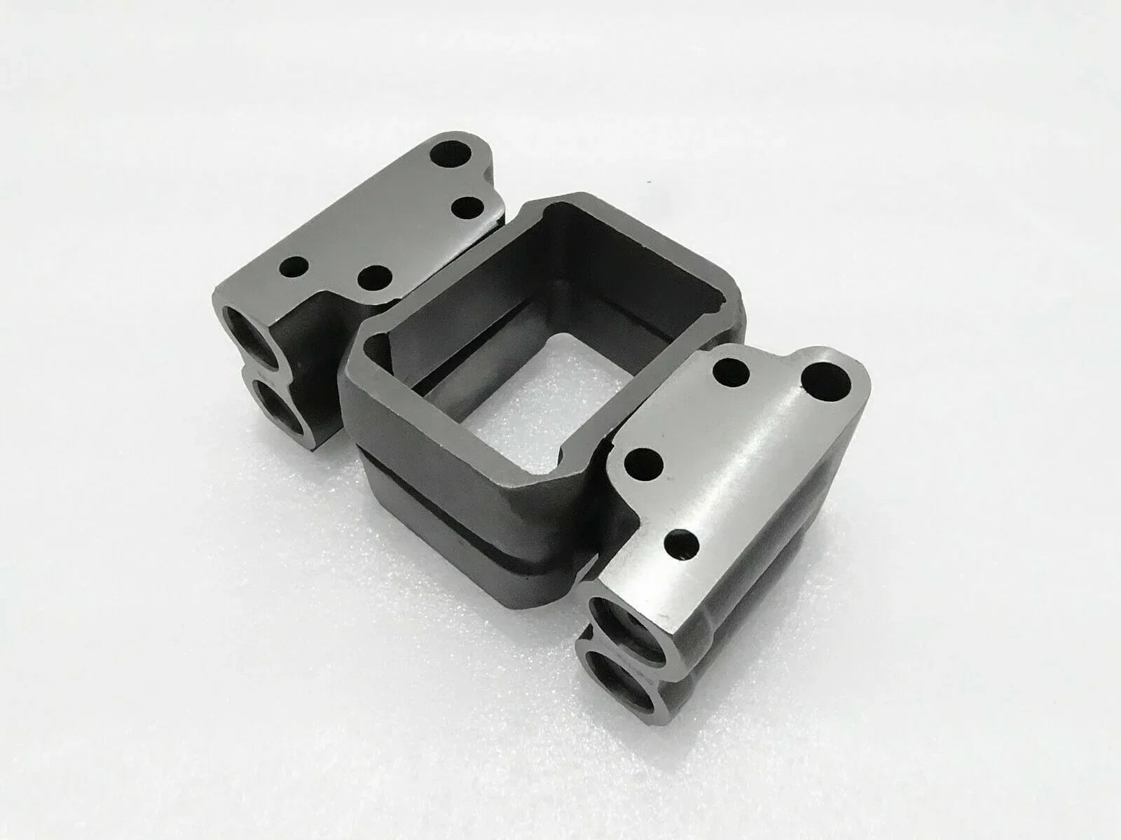 Hydraulic pump valve block with mounting flanges, metal and black finish.