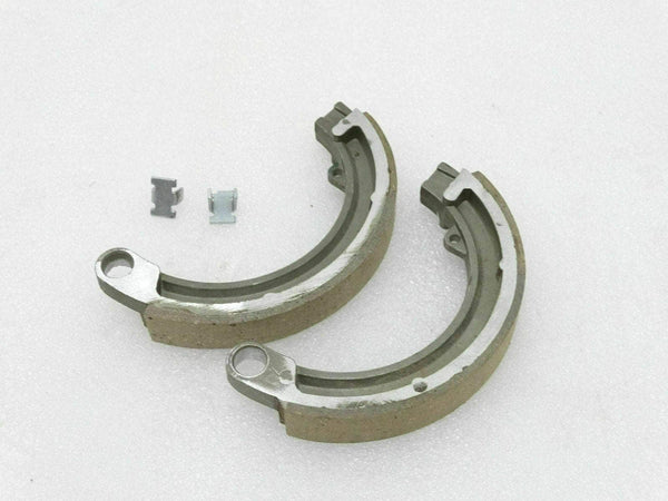 Front brake shoe kit with two curved brake shoes and metal clips