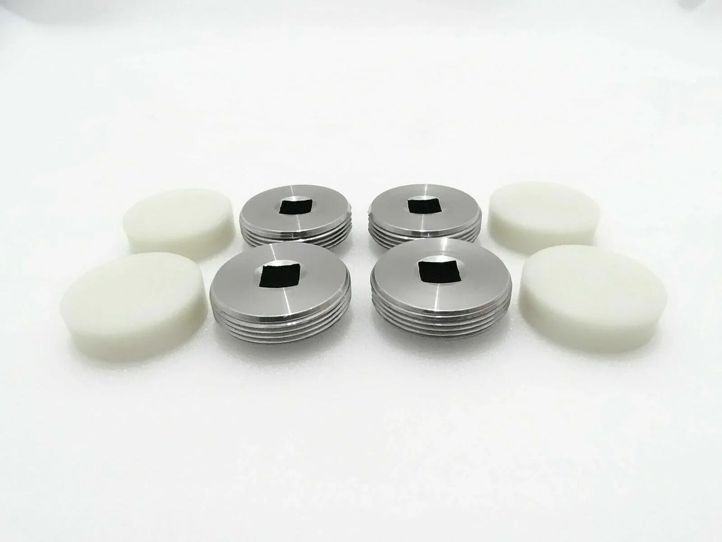 Set of 4 wear pads with white bases and silver metal caps.