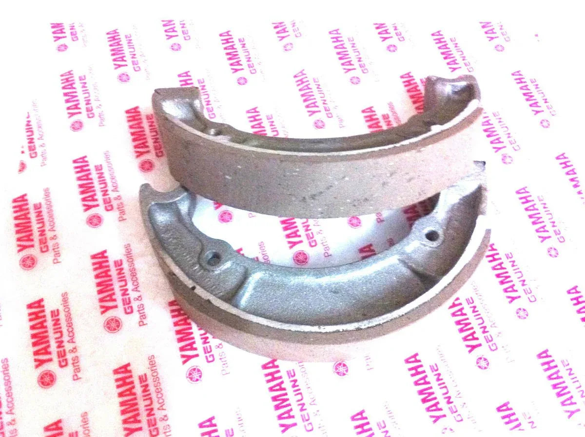 Motorcycle front brake shoe set with curved metal backing and friction lining