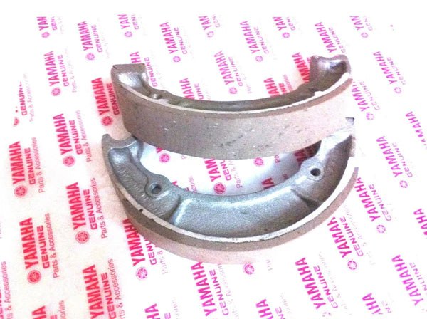 Motorcycle front brake shoe set with curved metal backing and friction lining