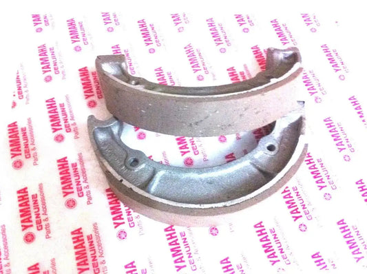 Motorcycle front brake shoe set with curved metal backing and friction lining