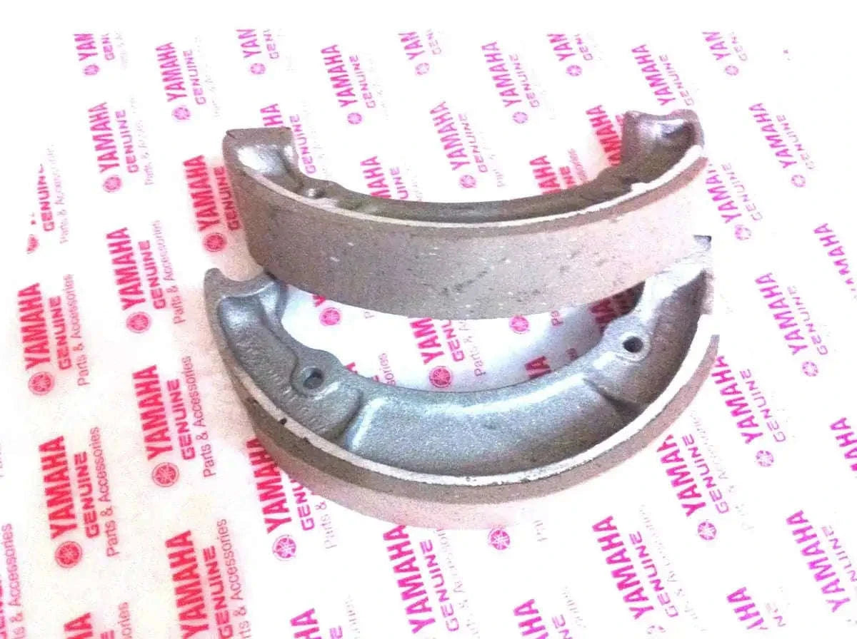 Motorcycle front brake shoe set with curved metal backing and friction lining